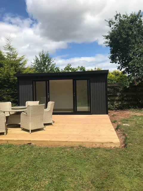 Dark clad garden room with wide glazed doors opening onto timber decking